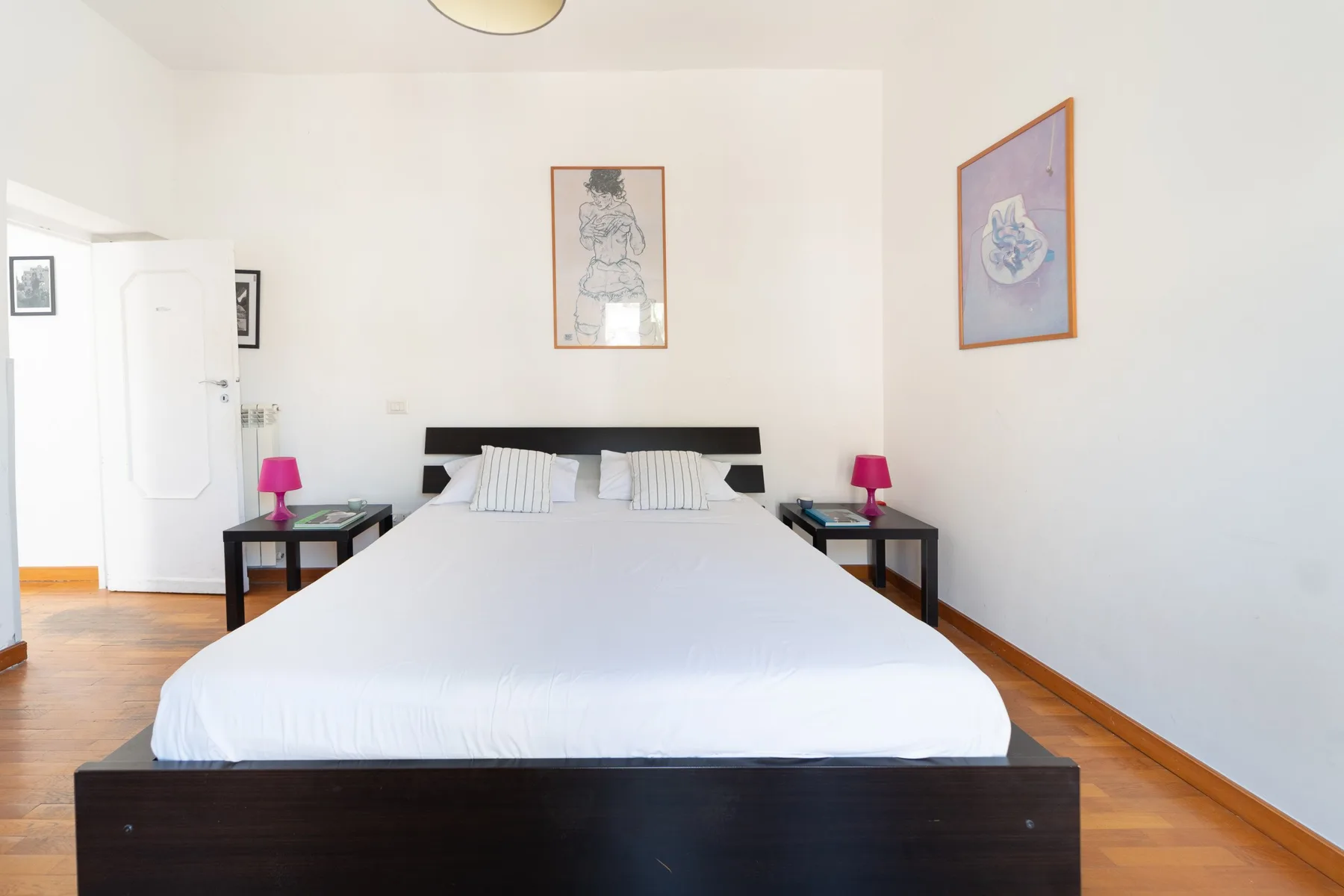 Dormitorio con una cama bien tendida y cuadros en las paredes.
