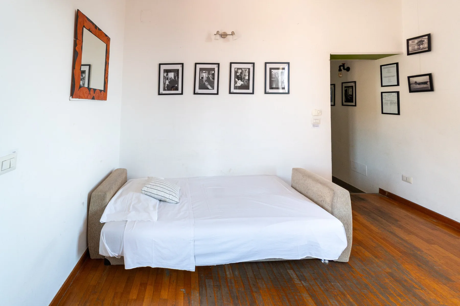 Un dormitorio con una cama bien tendida y cuadros enmarcados en la pared.