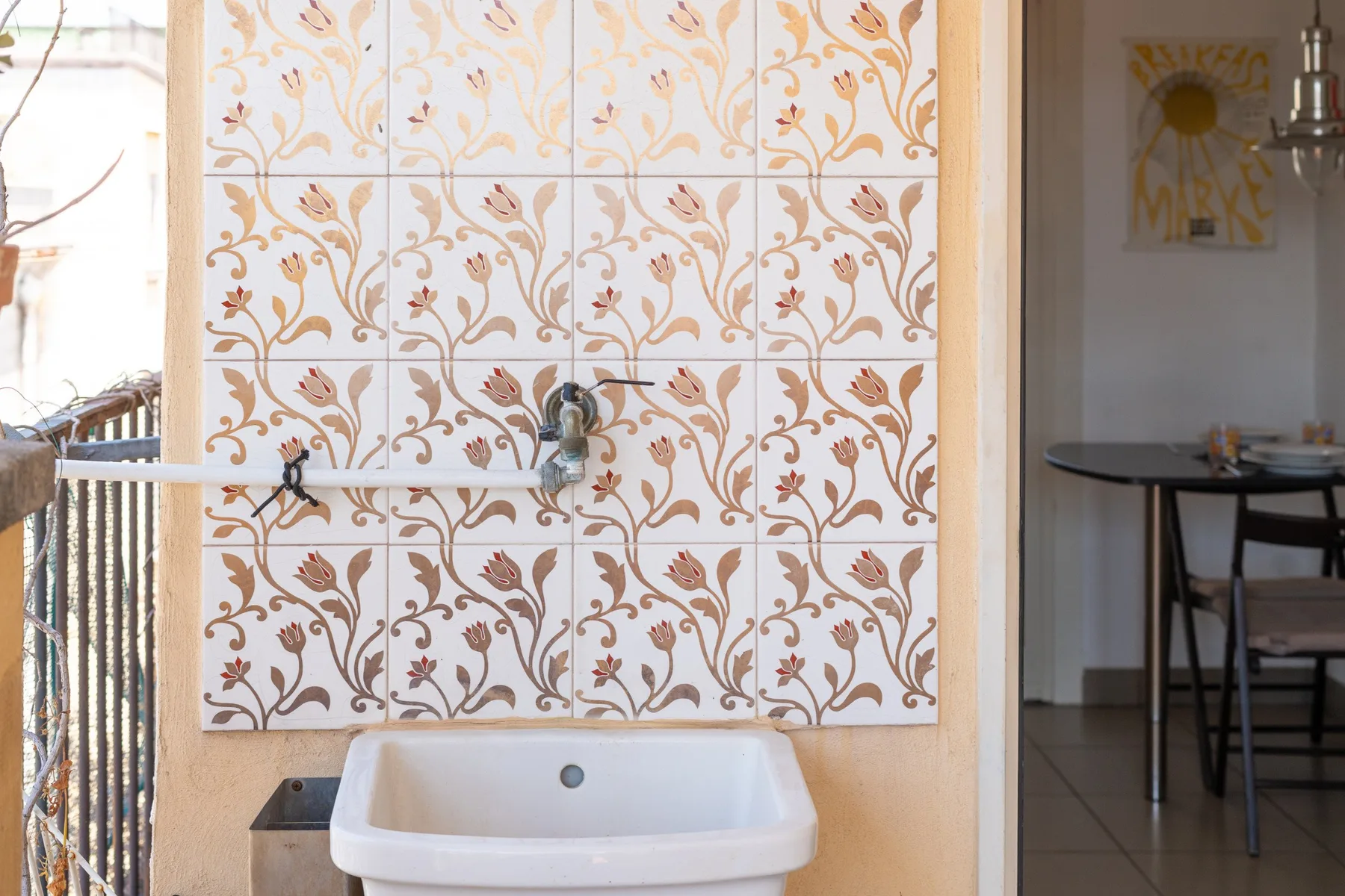 Un lavabo está frente a una pared de azulejos estampados, junto a un comedor.
