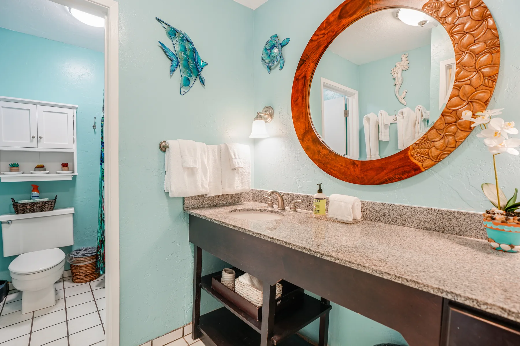 A bathroom vanity with a large round mirror and towels.