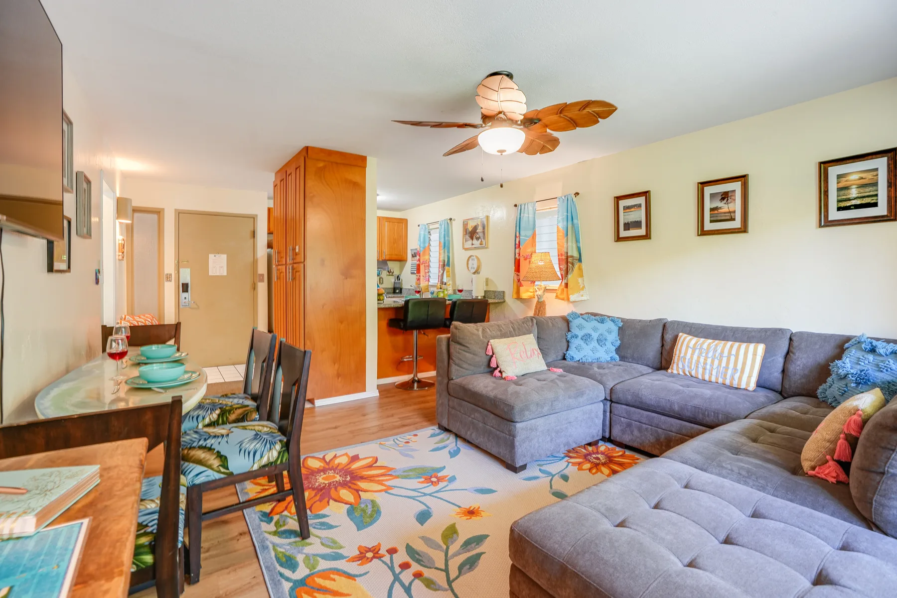 A living room with sectional seating, a dining table, and a colorful floral rug.