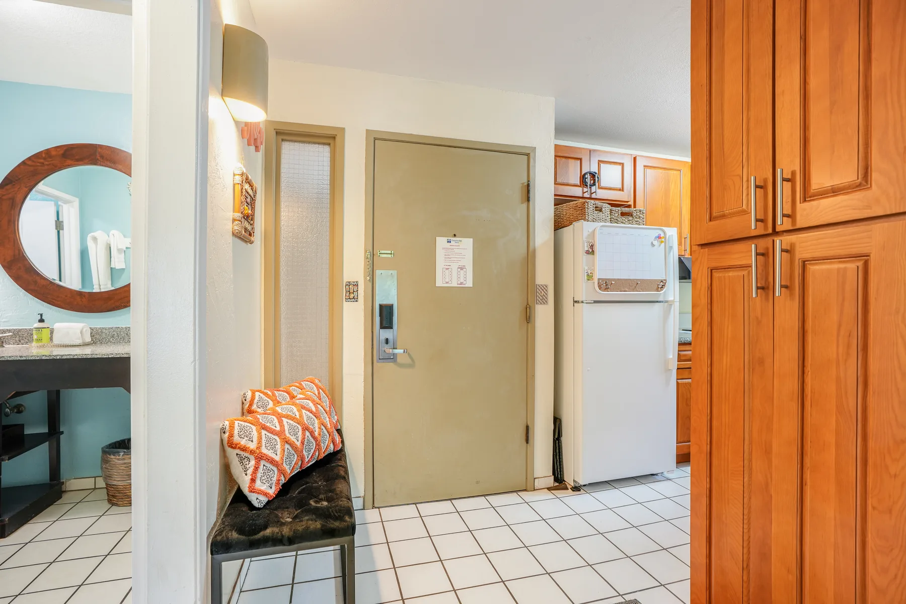 An interior entry area with a bench, a door, and a refrigerator.