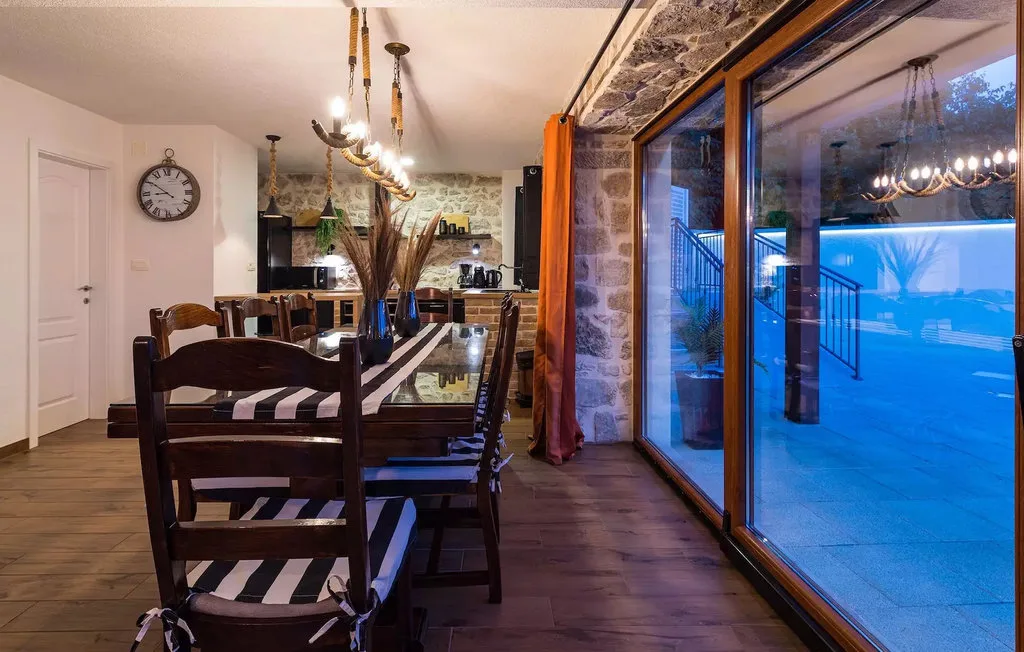 A dining area with a long table and large glass doors overlooking a snowy outdoor scene.