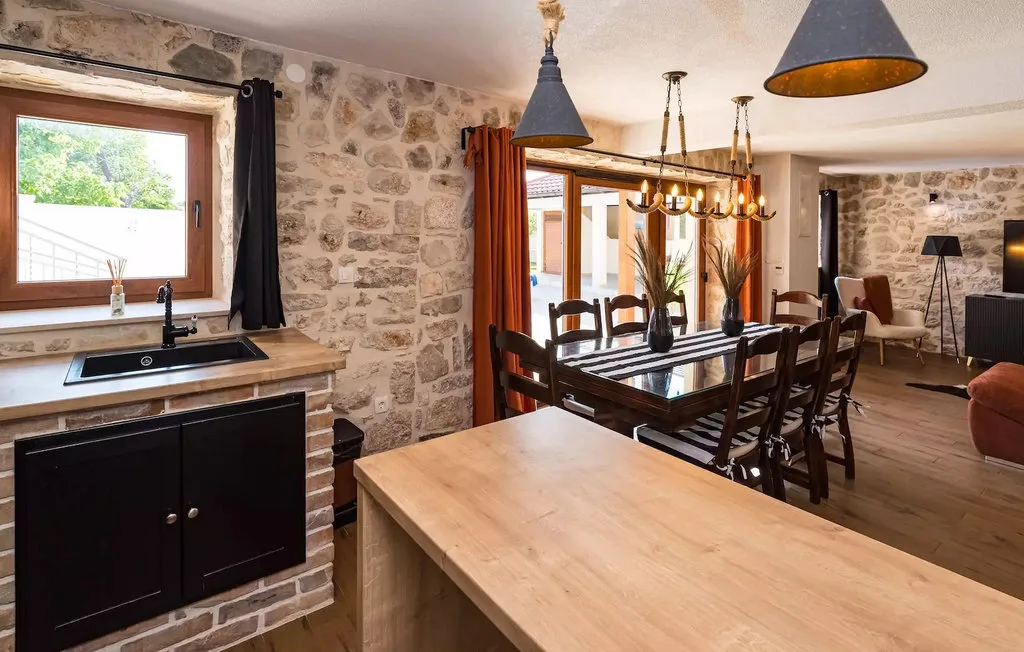 A stone-walled dining area with a long table and a kitchen counter.