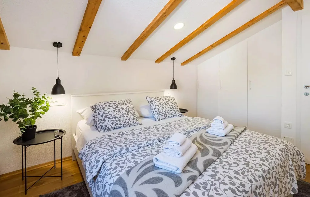 A bedroom with a double bed, patterned bedding, and exposed ceiling beams.