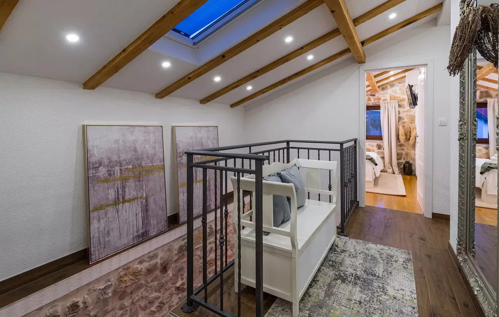 A loft bedroom with a skylight, exposed ceiling beams, and a bed.