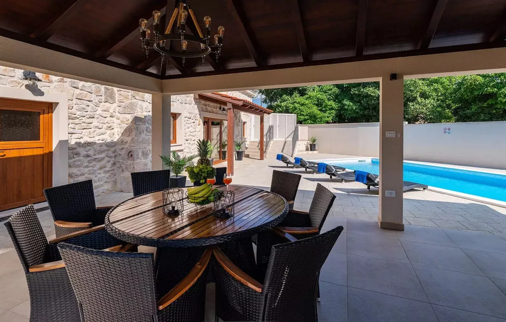 A covered outdoor dining area overlooks a swimming pool and patio.