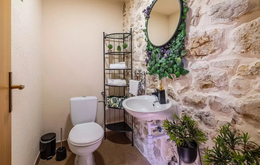 A bathroom with a toilet, sink, and stone accent wall.