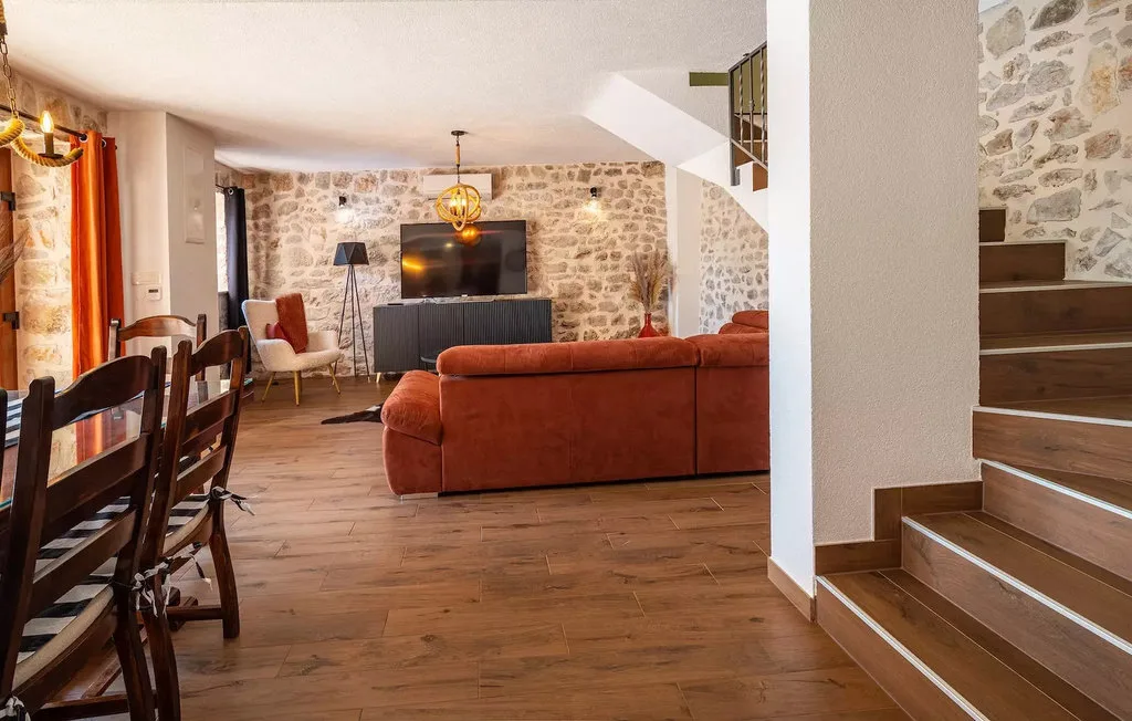 A living and dining area with seating, a television, and a staircase.