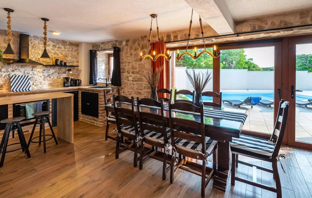 A dining area with a long table beside large glass doors opening onto a patio.