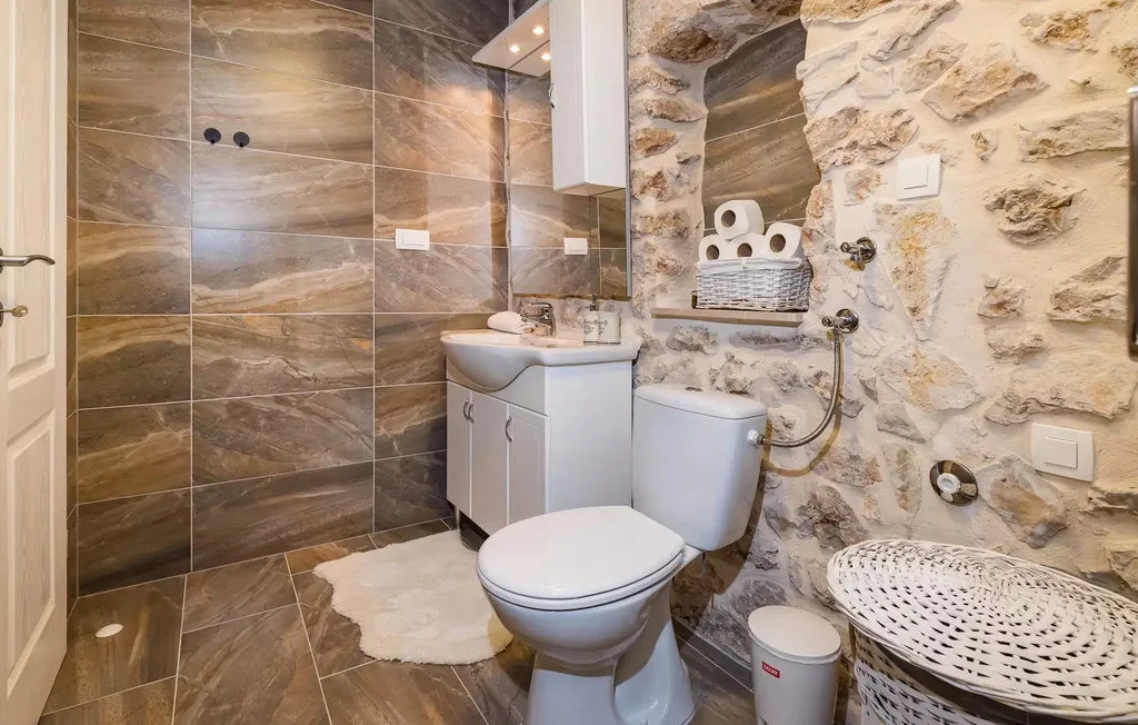 A bathroom with a sink, toilet, and stone walls.