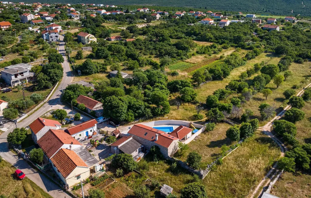 Aerial view of red-roofed homes among green fields and trees.