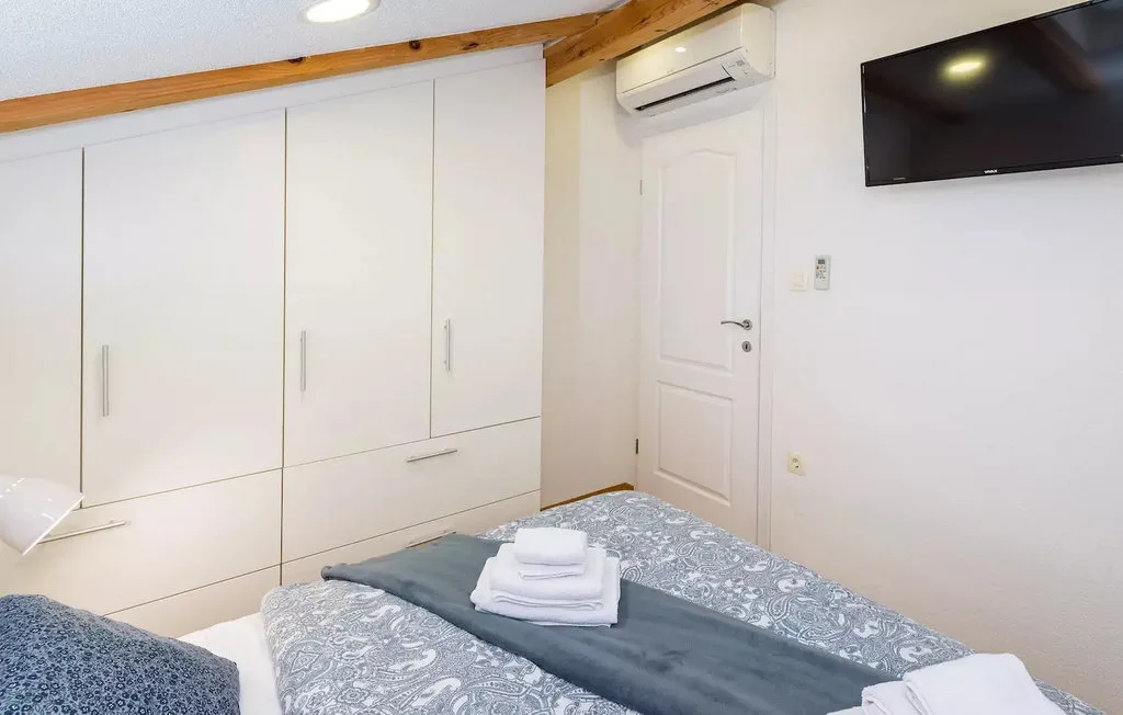 Bedroom with built-in white cabinets and a wall-mounted television.