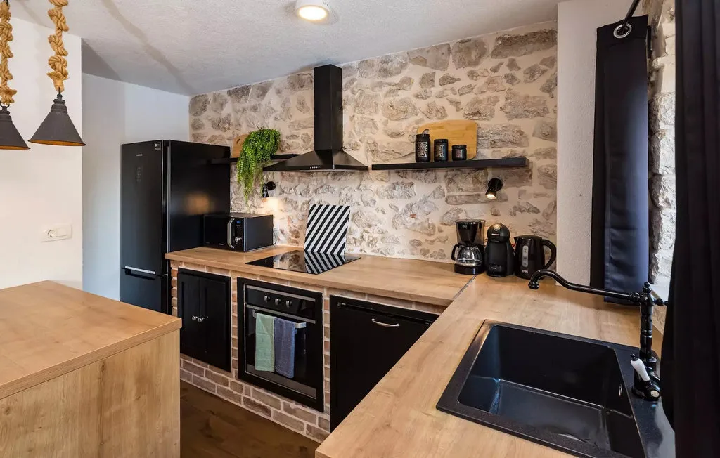 A kitchen with wooden countertops, dark cabinets, and a stone-patterned backsplash.