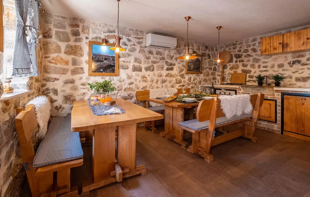 A rustic dining room with wooden tables, benches, and pendant lights.