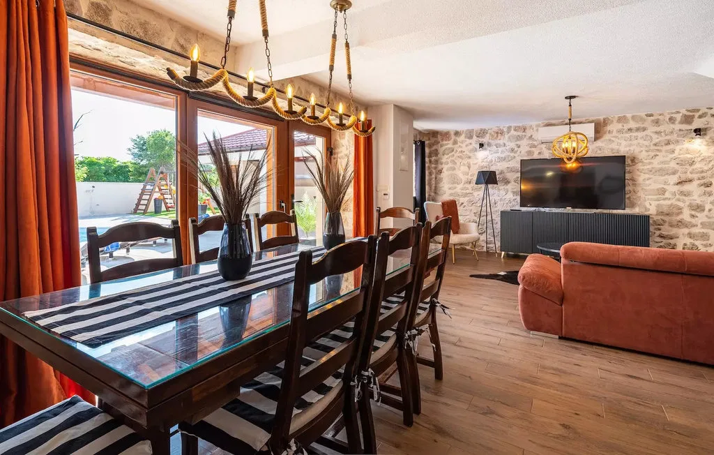A dining and living area with a long table, seating, and a television.