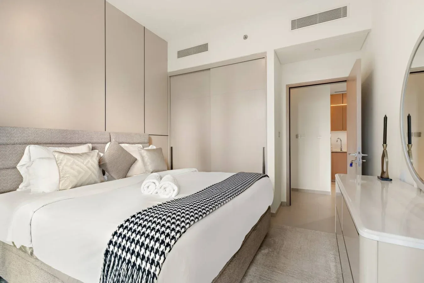 Un dormitorio con ropa de cama blanca y una manta estampada sobre la cama.