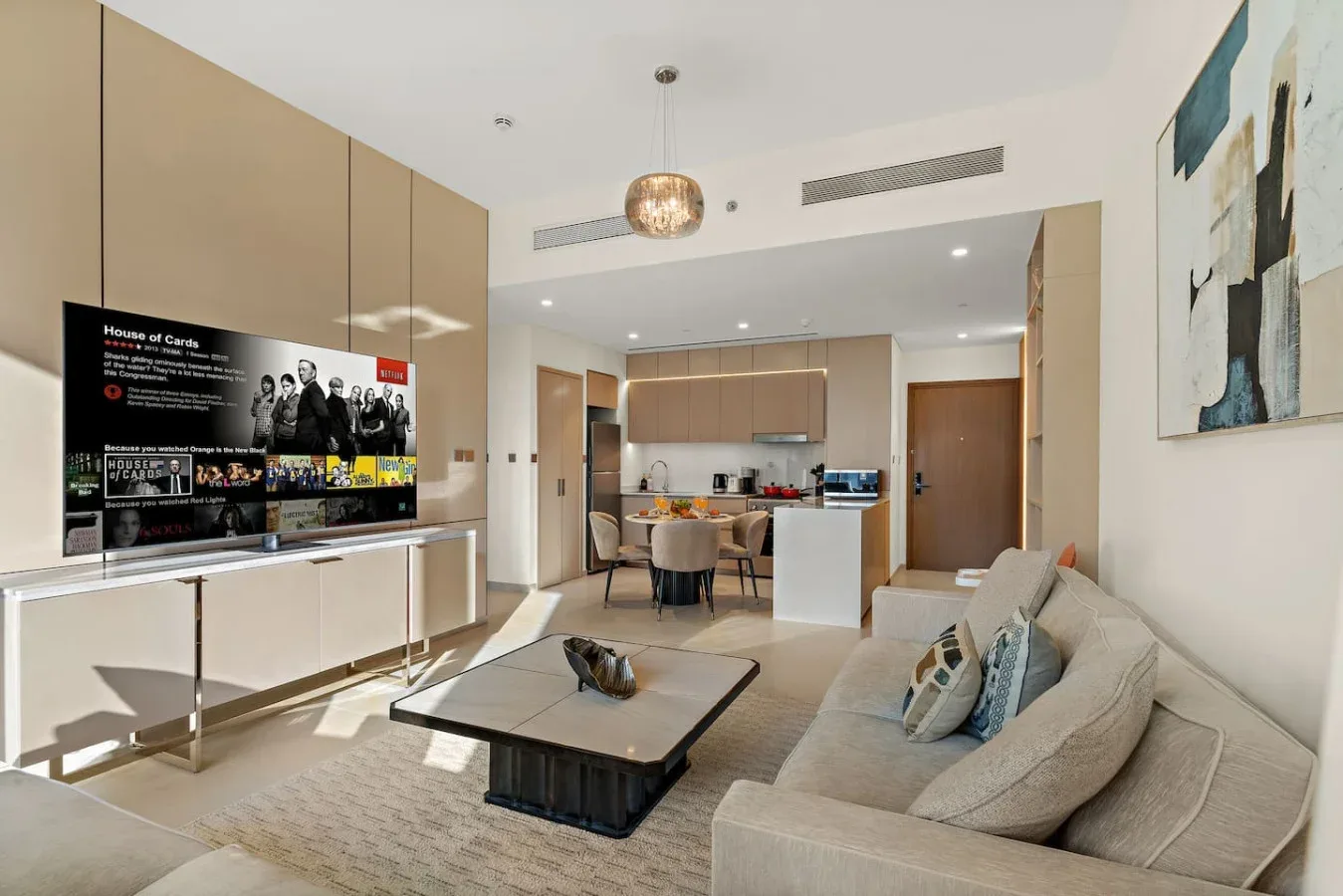 Una luminosa sala de estar con televisor, asientos y una cocina abierta.