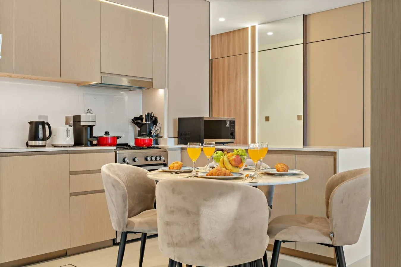 Un comedor con la mesa puesta está frente a una cocina moderna.
