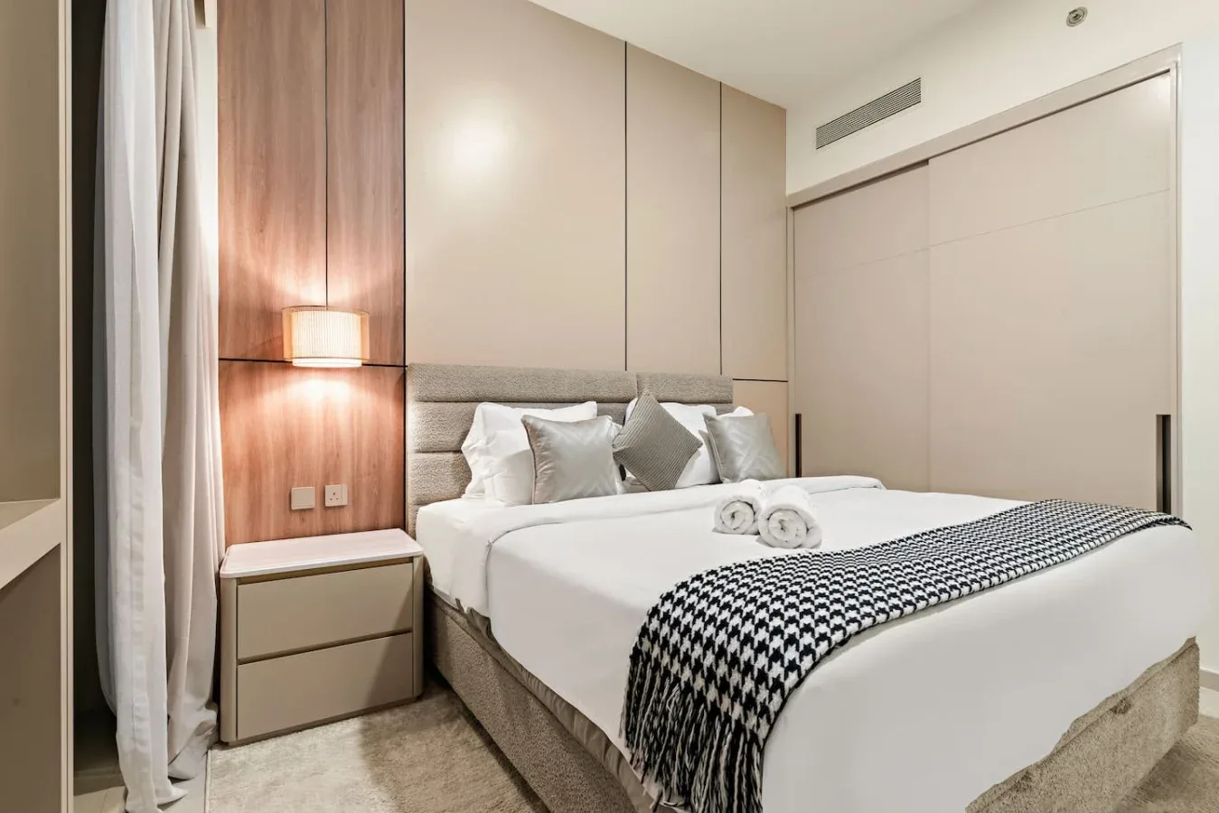 Un dormitorio con una cama bien tendida y una lámpara de noche.