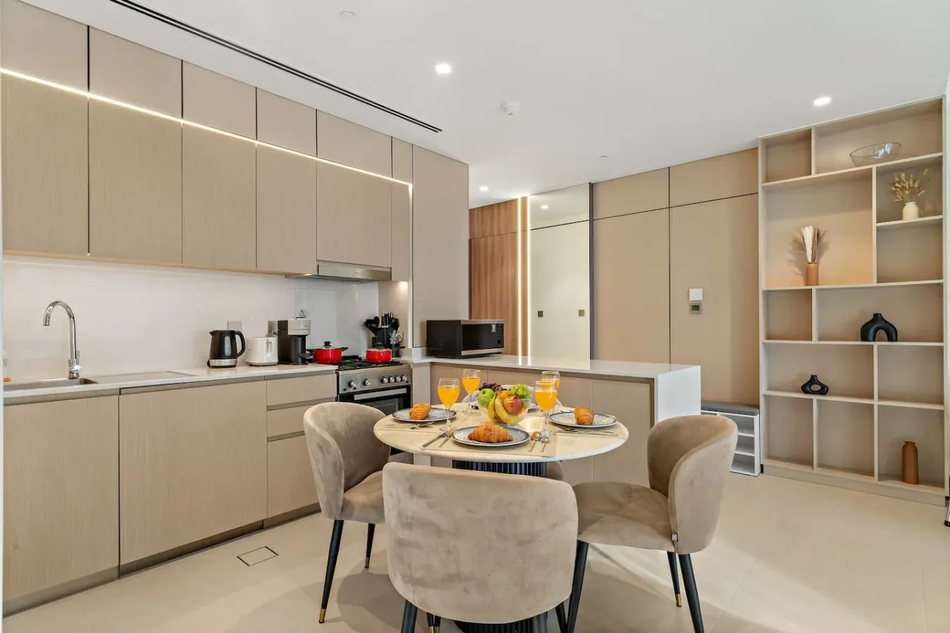 Una cocina moderna y zona de comedor con una mesa central y estanterías empotradas.