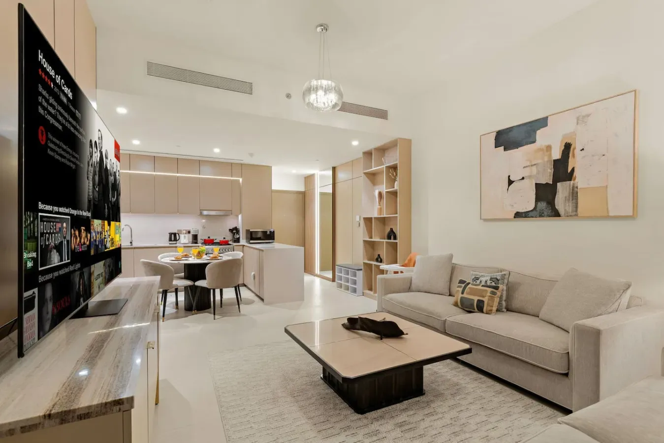 Sala de estar de concepto abierto con zona de asientos, mesa de centro y cocina al fondo.