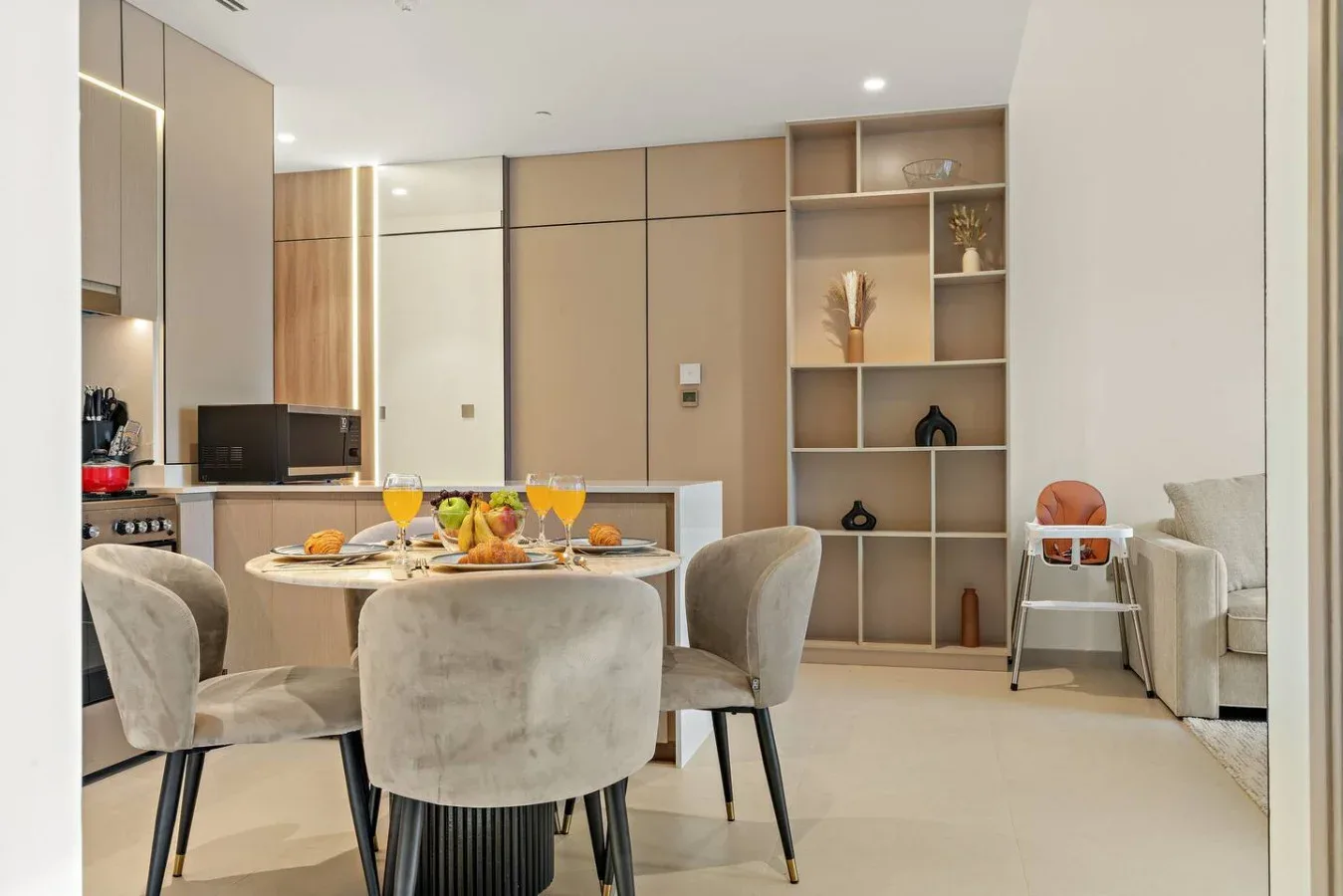 Una luminosa zona abierta de comedor y cocina, con la mesa puesta y estanterías empotradas.