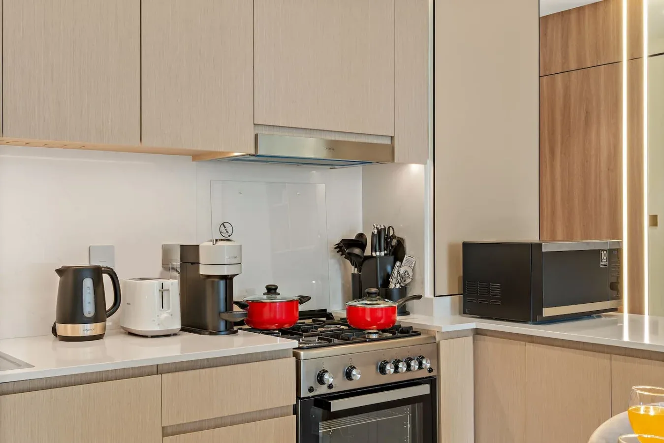 Una cocina moderna con estufa, electrodomésticos de encimera y gabinetes de madera clara.