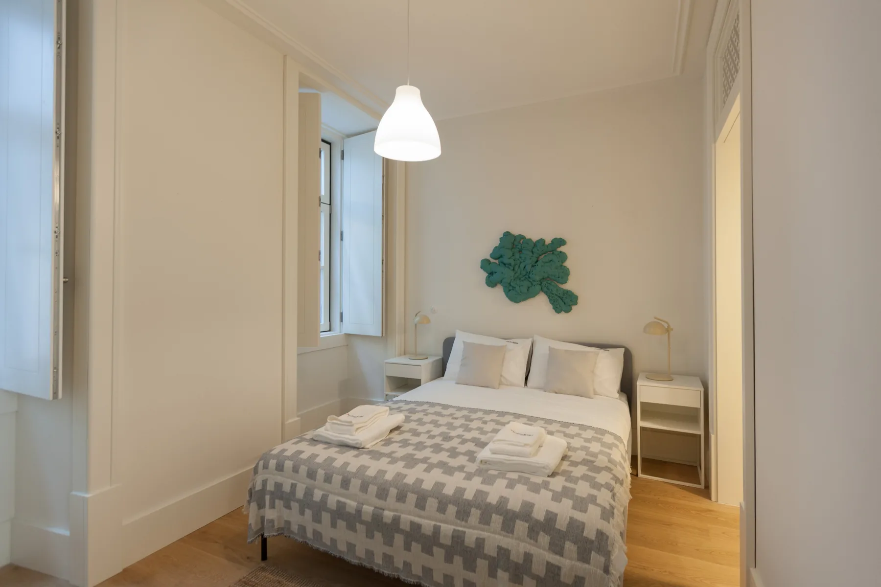 Un dormitorio con una cama doble, mesitas de noche y una ventana.