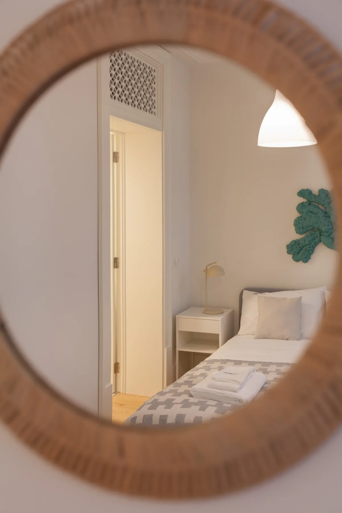 Un dormitorio con una cama bien arreglada y una pequeña mesa de noche.