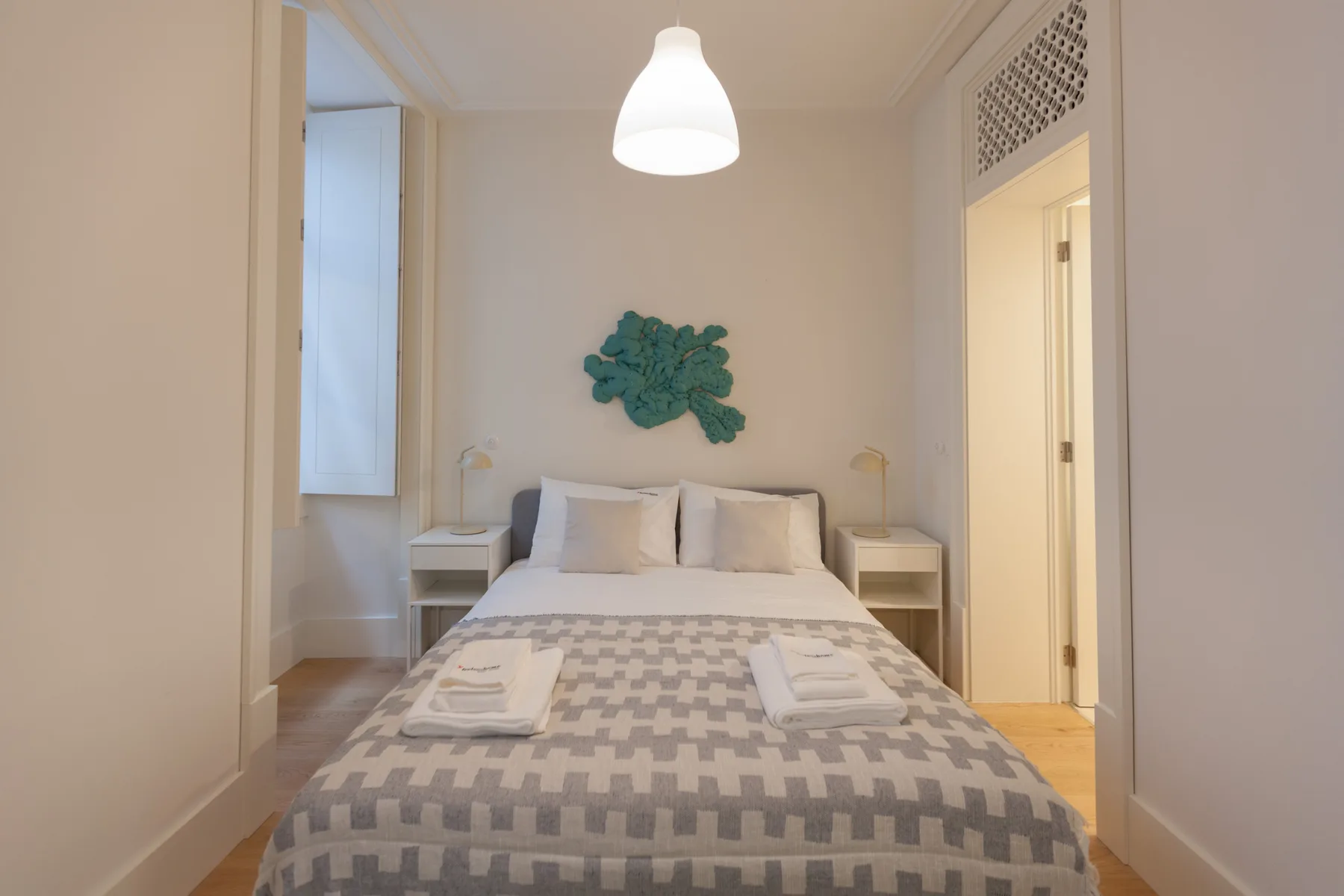 Un dormitorio con una cama, mesillas de noche y una ventana.