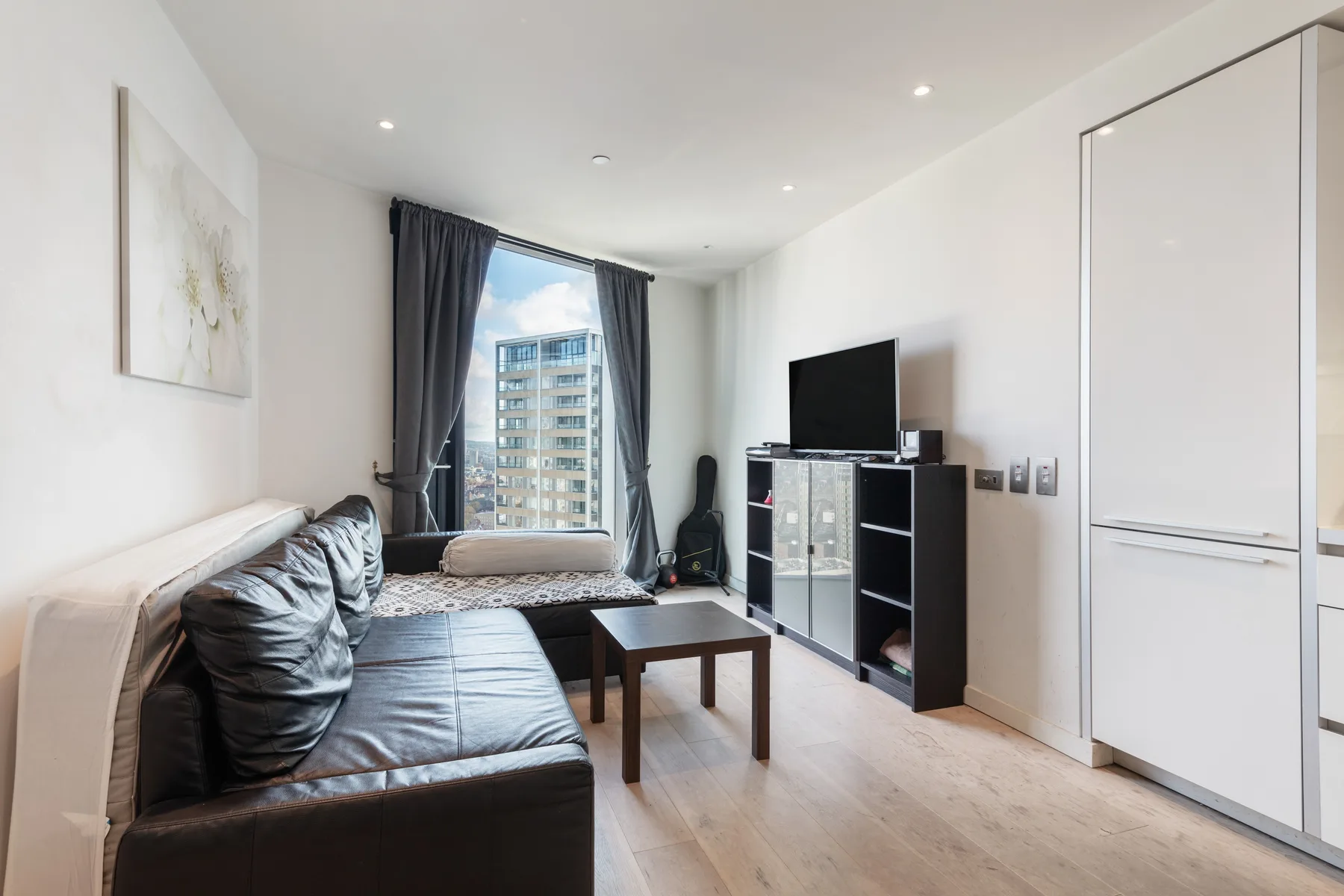 Una sala luminosa con asientos, una mesa de centro y un televisor junto a la ventana.