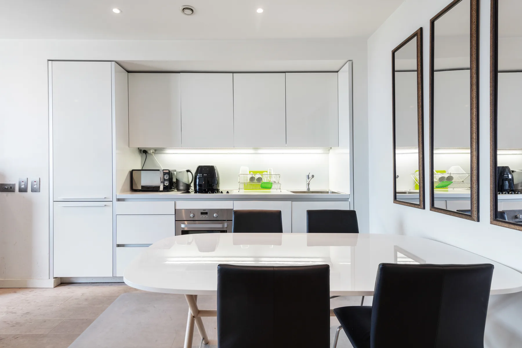 Una cocina y comedor luminosos con armarios blancos y una mesa.
