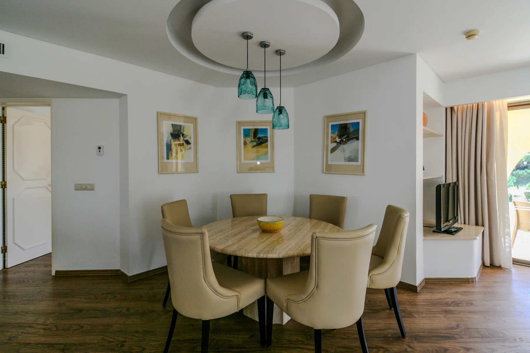 A dining area with a round table, chairs, and pendant lights.