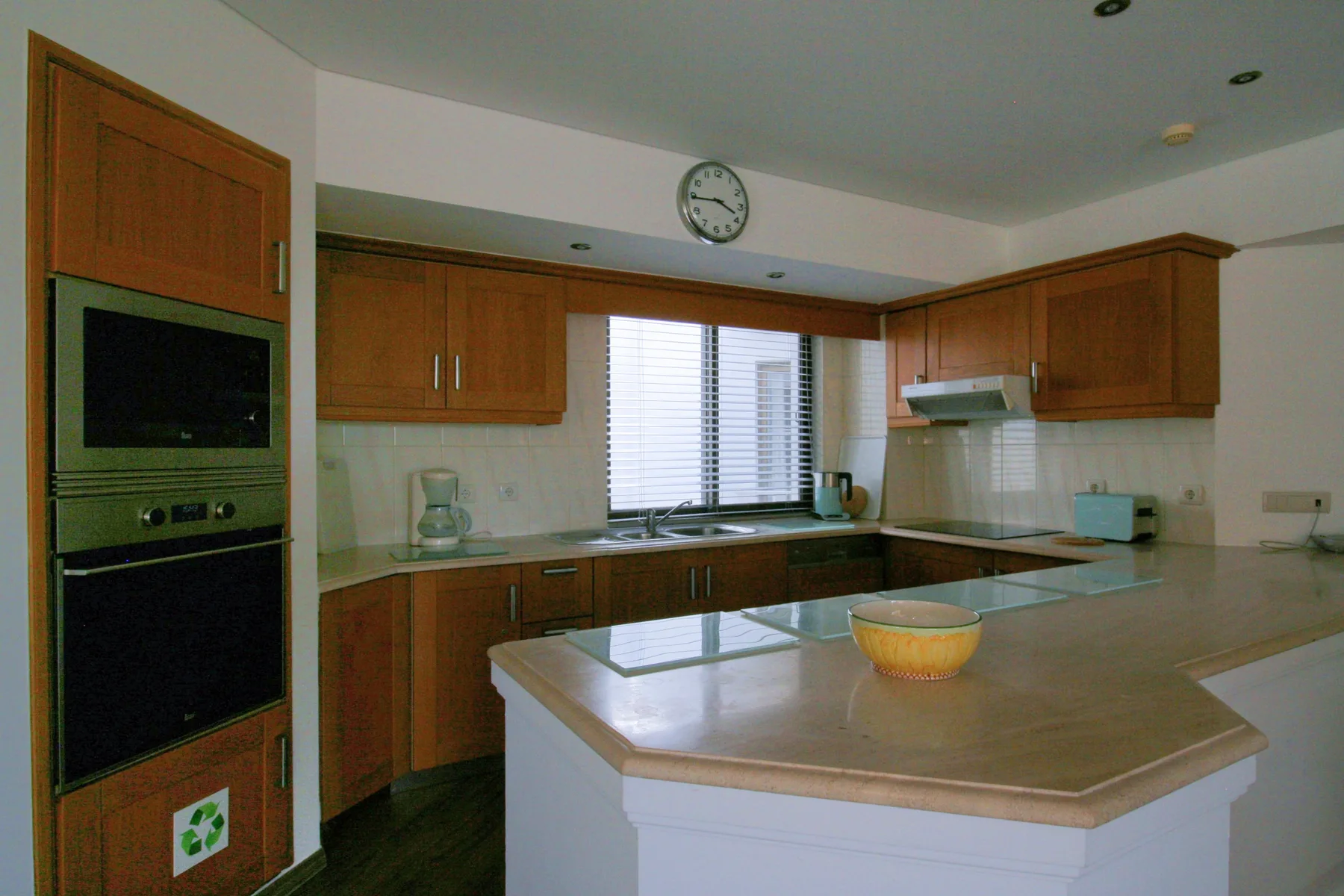 A kitchen with wooden cabinets and a central countertop.