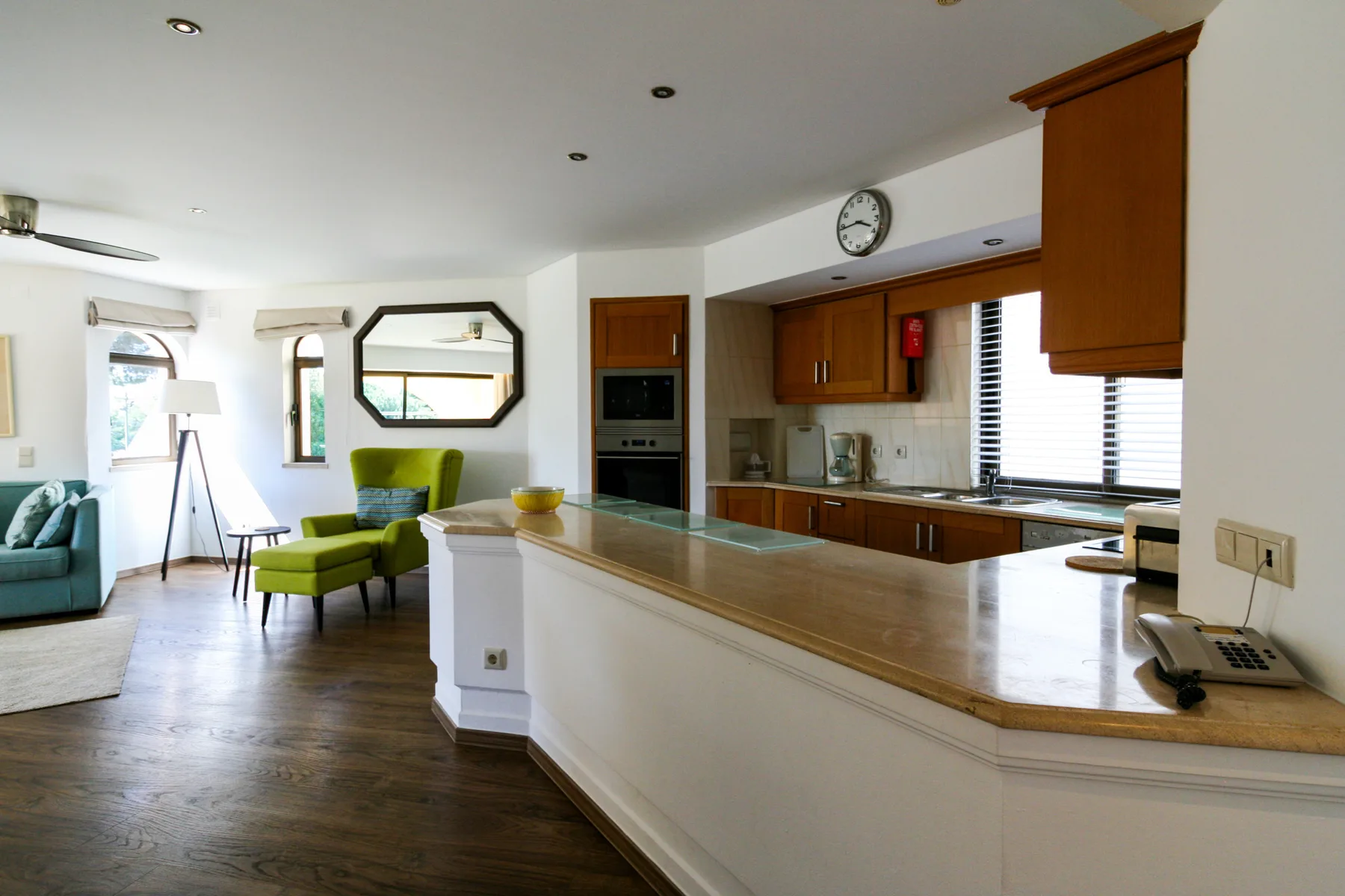 An open-plan kitchen and living area with a long counter and green seating.