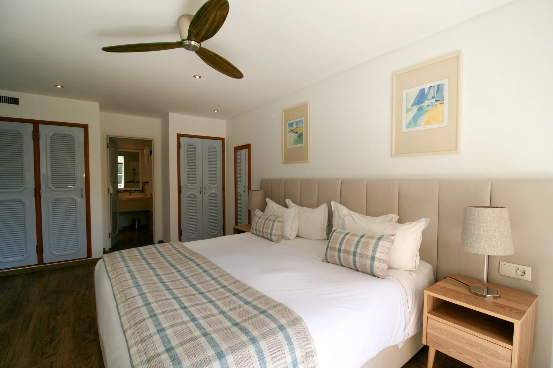 A bedroom with a large bed, patterned bedding, and a bedside table.