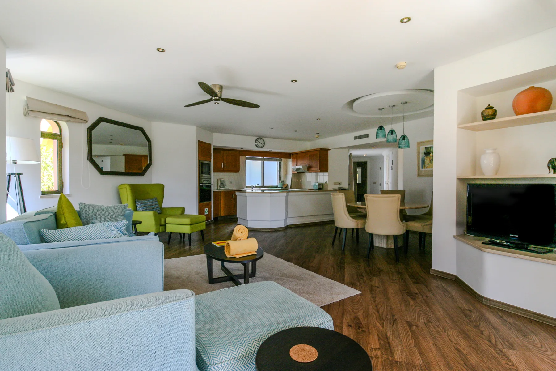 An open-plan living room and kitchen with seating, a dining table, and a television.