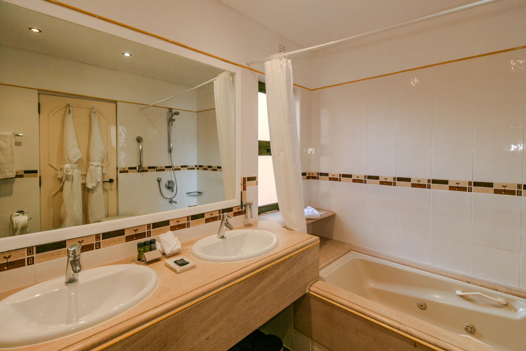 A tiled bathroom with a double sink vanity and a bathtub.