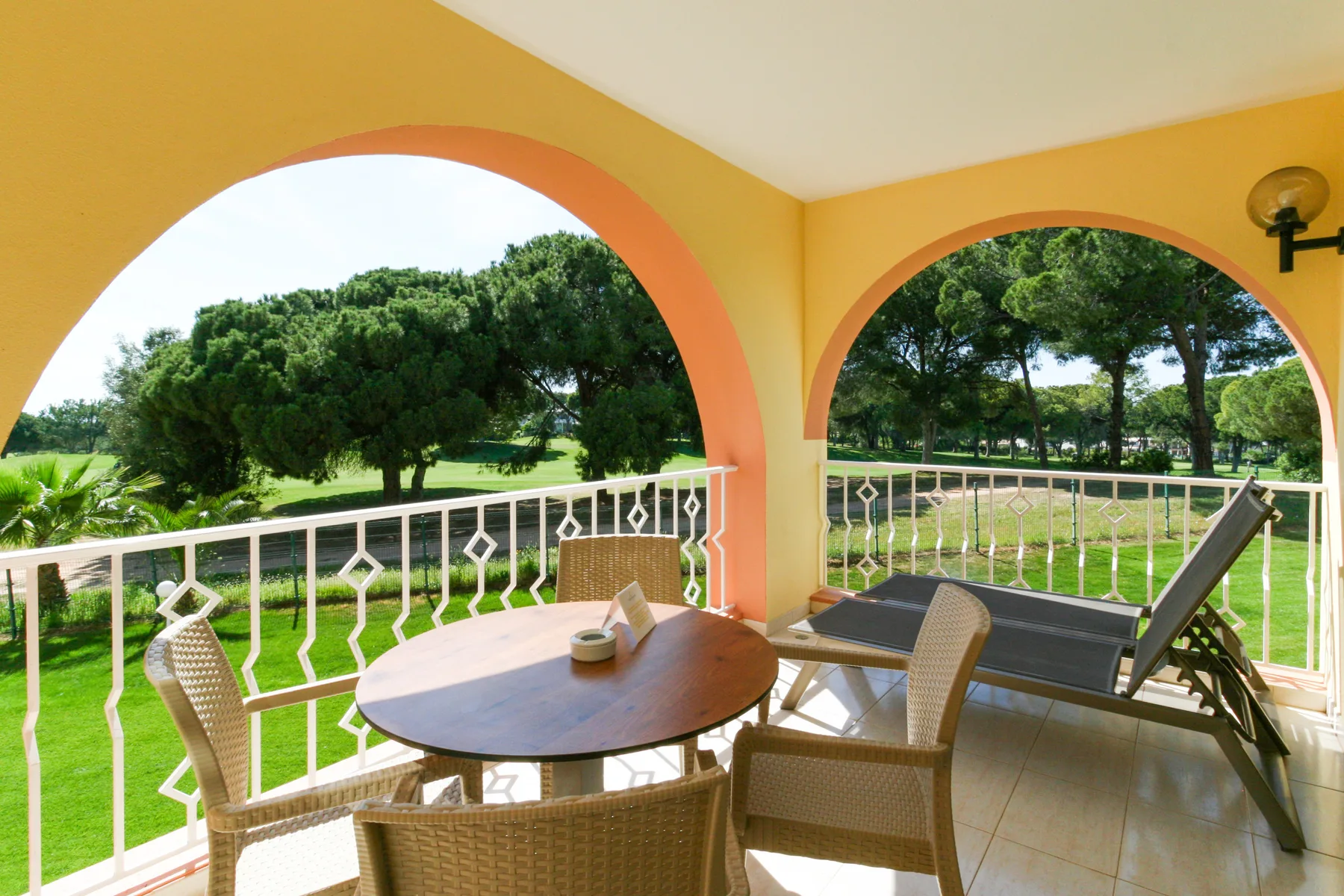 Covered patio with a dining table and seating overlooking green grounds.