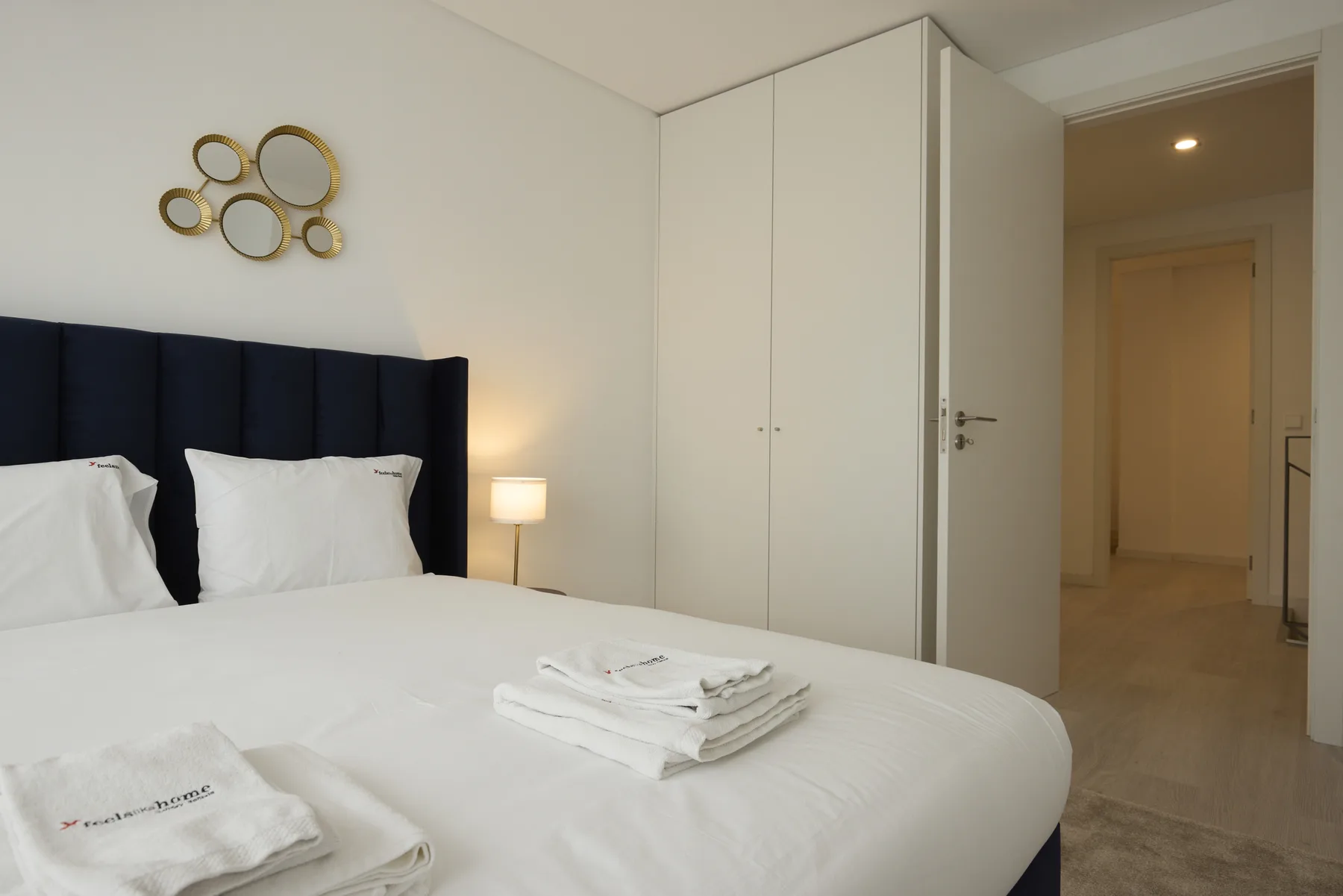 Un dormitorio con una cama, toallas dobladas y un armario.