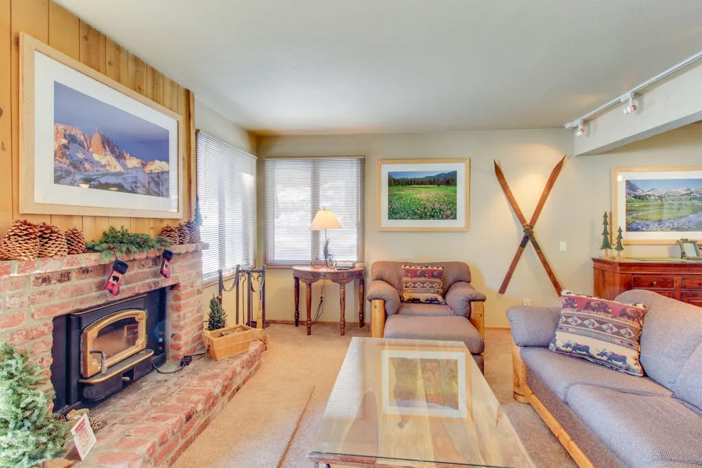 A living room with a brick fireplace, seating, and a glass coffee table.