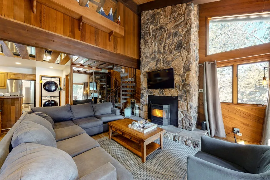 A rustic living room with sectional seating and a stone fireplace.