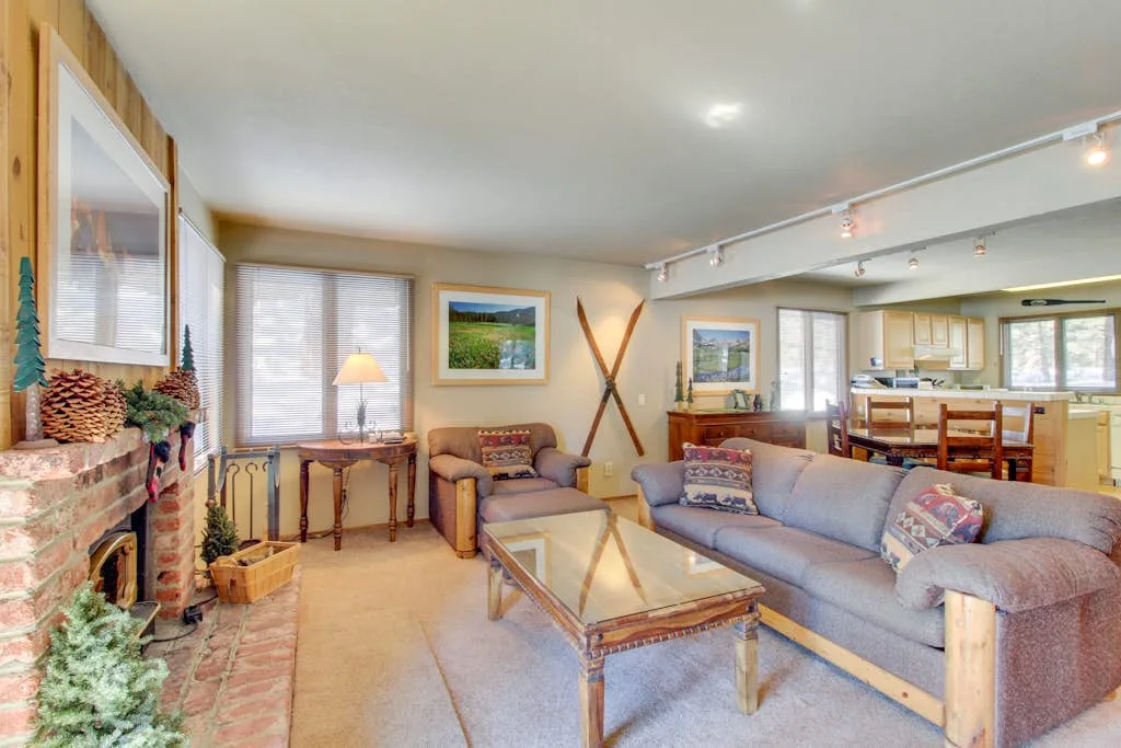 A living room with seating around a glass coffee table beside a brick fireplace.