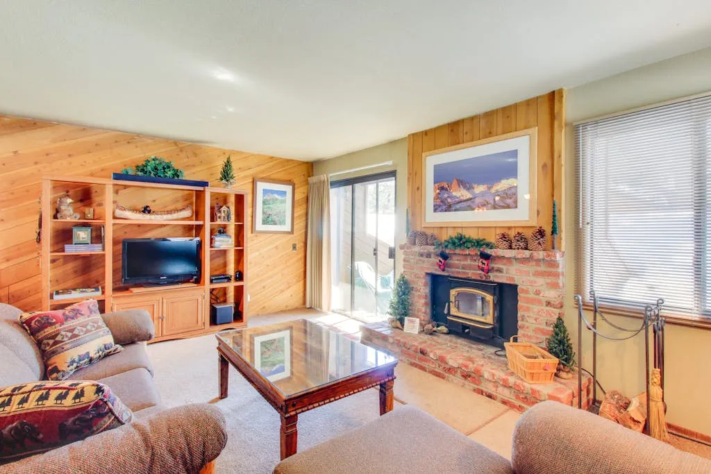 A wood-paneled living room with a fireplace and glass coffee table.
