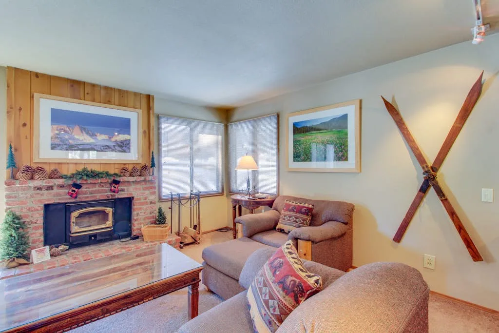 A living room with seating, a brick fireplace, and windows.