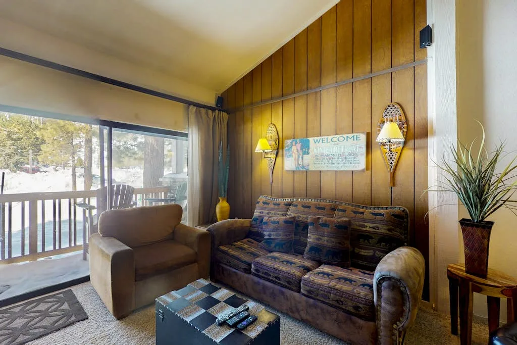 A wood-paneled living room with a patterned couch and a large window.