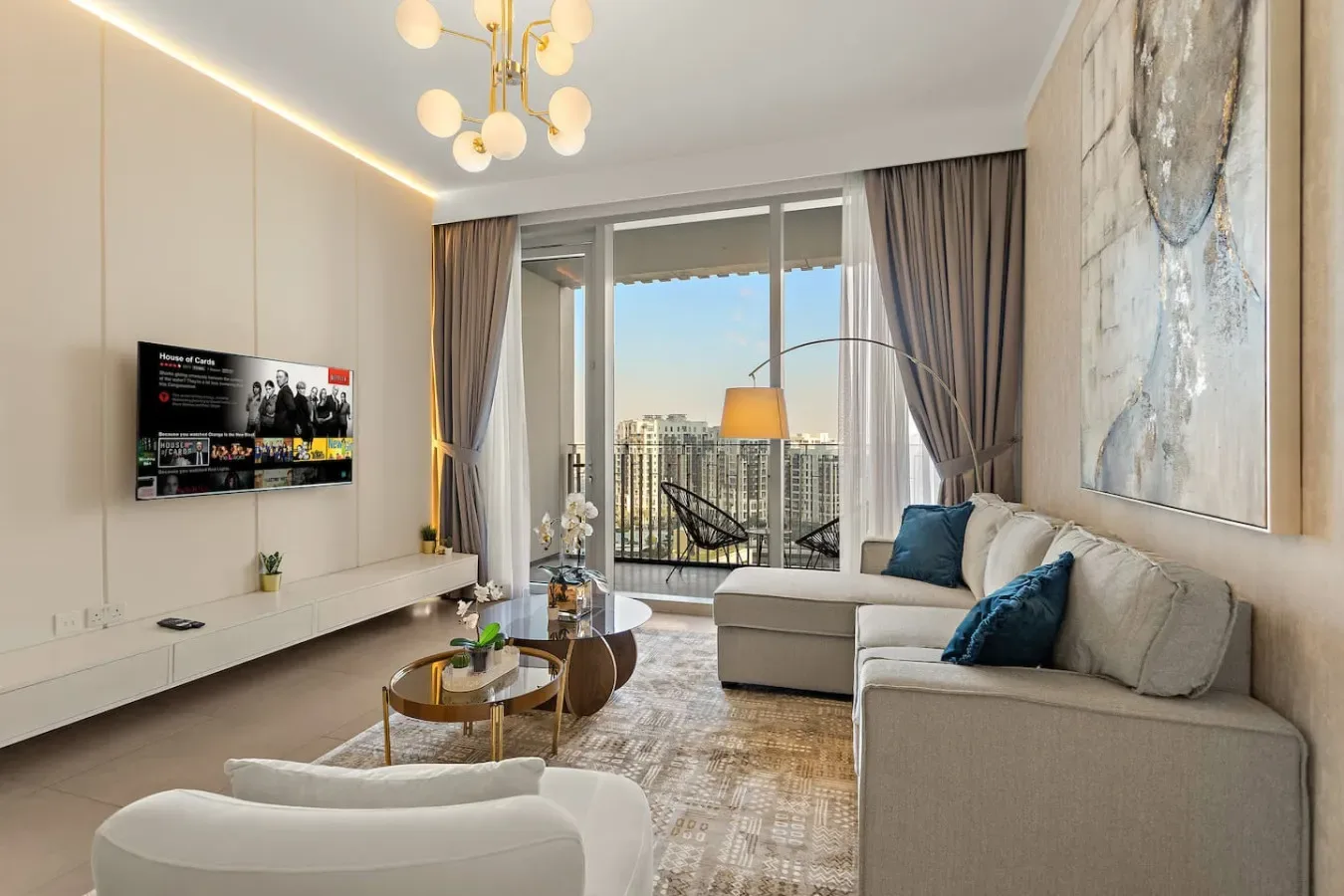 Una sala luminosa con asientos, un televisor y grandes ventanales con vistas a edificios de la ciudad.