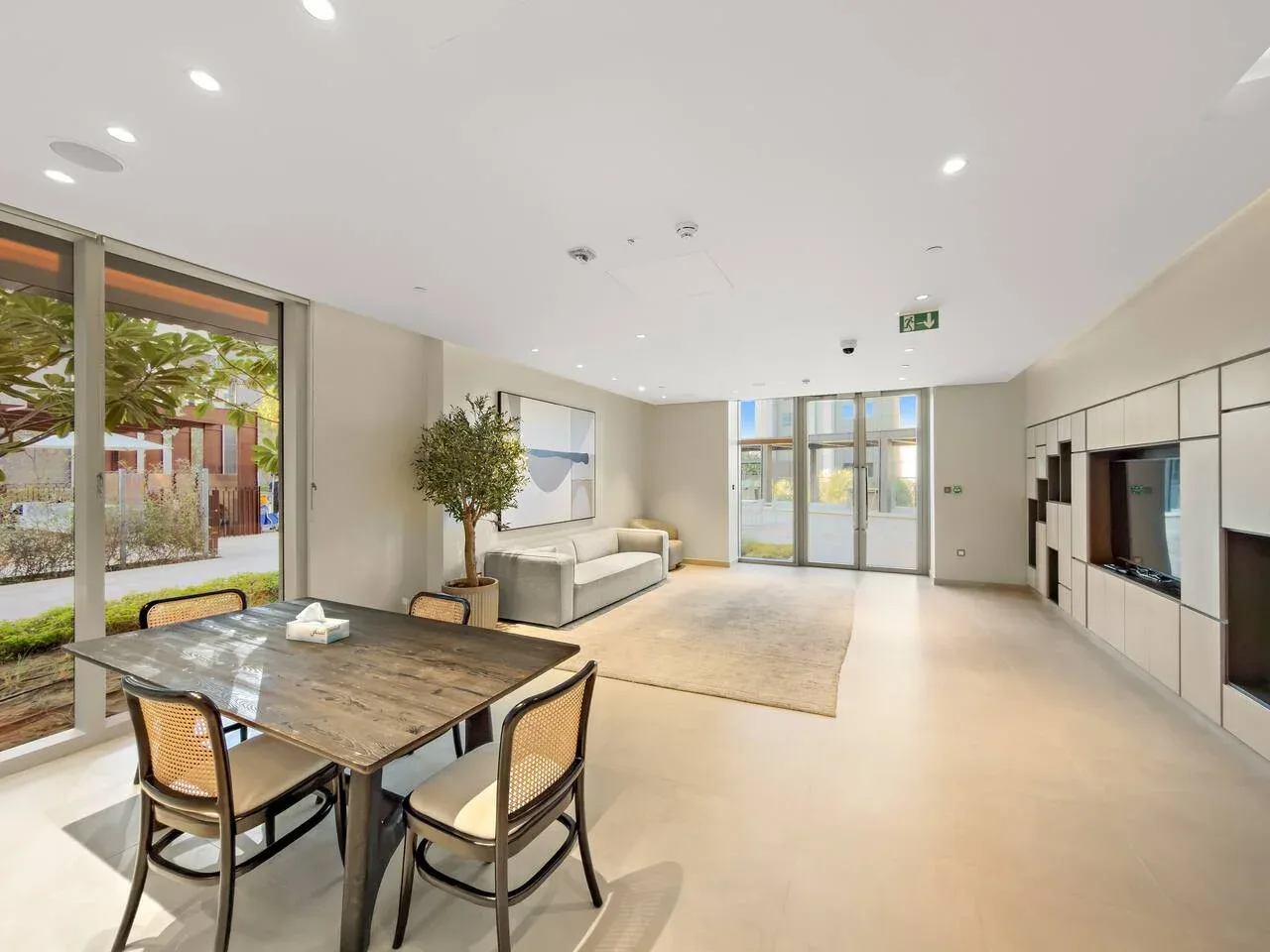 Una luminosa sala de estar y comedor diáfana con mesa, asientos y grandes ventanas.