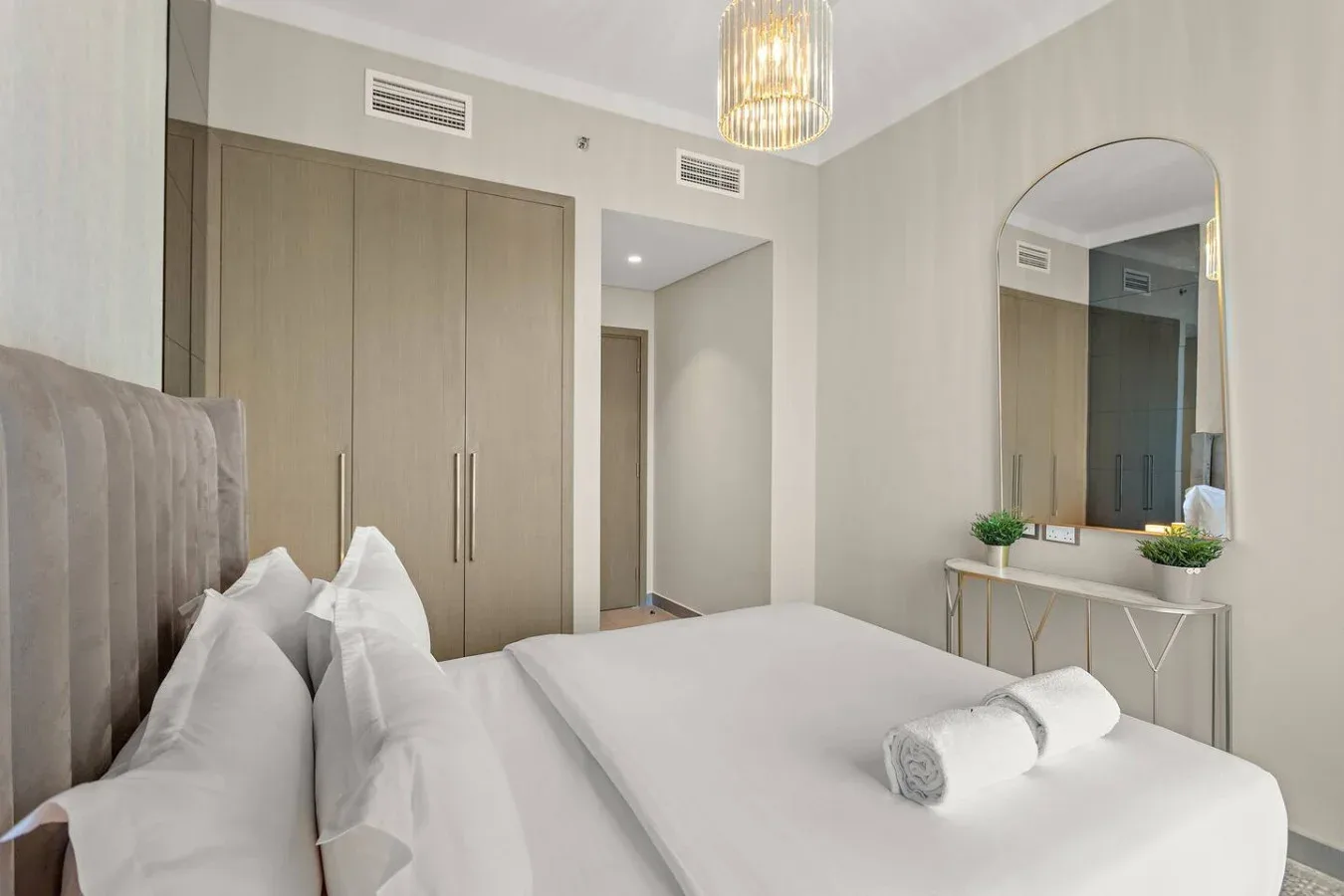 Un dormitorio con una cama tendida, un armario y un tocador.